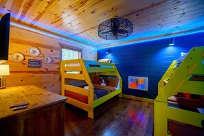Upstairs bunk room at Double J Hideaway features 2 Twin-over-Full bunks, color-changing LED lights, and a wall-mounted Lite Brite for extra fun.