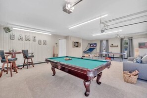 Game on! Enjoy endless entertainment in this action-packed garage game room, complete with hoops, foosball, ping pong, and billiards—perfect for friendly competition.