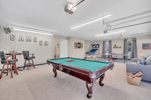 Game on! Enjoy endless entertainment in this action-packed garage game room, complete with hoops, foosball, ping pong, and billiards—perfect for friendly competition.