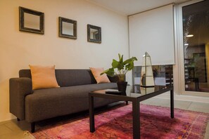 Relax in style with this chic living room featuring a comfy sofa, vibrant rug, and lush greenery, perfect for unwinding after a day of adventure.