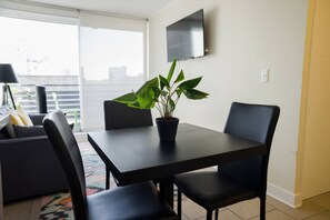 Cozy dining area with a modern touch, perfect for intimate meals. Enjoy natural light and entertainment with a wall-mounted TV.