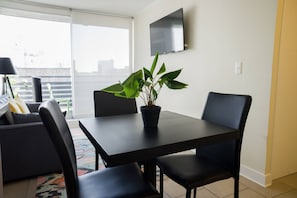 Cozy dining area with a modern touch, perfect for intimate meals. Enjoy natural light and entertainment with a wall-mounted TV.