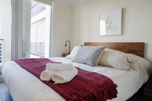 Relax in this cozy bedroom with a plush bed, modern decor, and a view of the balcony. Perfect for a restful stay in the heart of Chile.