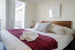 Relax in this cozy bedroom with a plush bed, modern decor, and a view of the balcony. Perfect for a restful stay in the heart of Chile.