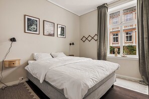 Bright and spacious master bedroom featuring premium bedding and street views.
