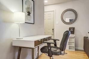 Dedicated workspace in the living room with a desk, lamp, and comfortable chair for remote work or planning your day.
