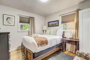 Primary bedroom with a plush bed, soft lighting, and dual windows that bring in fresh air and gentle morning sun.

