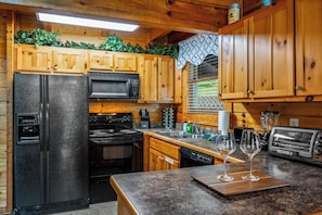 Prepare delicious meals in this fully equipped kitchen, featuring ample counter space and all the appliances you need for a comfortable stay. The warm wooden cabinetry adds to the rustic charm, making cooking a pleasure.