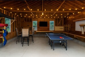 Spacious garage game room featuring ping pong, ski ball, TV, and kayak storage—fun for all ages!