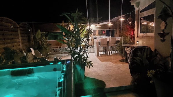La terrasse avec ses lumières tamisées promet de belles soirées. Le jacuzzi apporte un confort supplémentaire et les plantes ajoutent une touche naturelle apaisante. Parfait pour se détendre sous les étoiles.