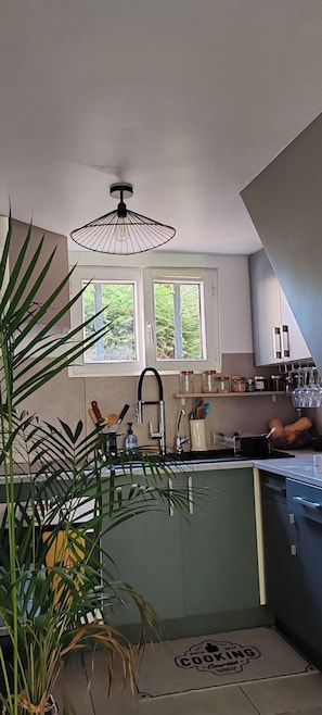 Le tapis "Cooking Course" ajoute une touche ludique. Profitez de la cuisine bien aménagée qui offre une vue sur le jardin depuis la fenêtre, idéale pour cuisiner avec sérénité et inspiration.