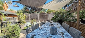 Cette terrasse offre un espace zen parfait pour des dîners. La végétation luxuriante et le buste apaisant invitent à la relaxation. Imaginez déguster un repas sous la toile d'ombrage, bercé par une douce brise.