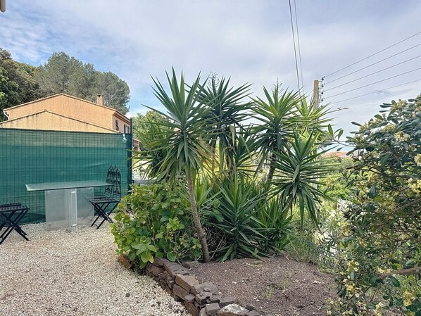 Immergez-vous dans cet oasis extérieur paisible. Profitez du café matinal entouré de végétation luxuriante et de mobilier en plein air. La barrière verte ajoute de l'intimité à cet espace tranquille.