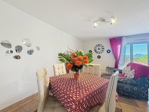 La pièce offre un cadre lumineux et décoratif, idéal pour des repas. Les chaises confortables invitent à prolonger les moments de détente.
