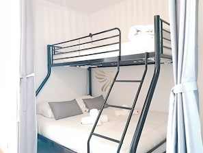 Espace nuit avec lit superposé double en bas et simple en haut, idéal pour familles. Rideaux occultants et ambiance douce pour des nuits paisibles.