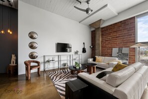 Spacious and stylish living room with large windows and modern furnishings, unwind in comfort.