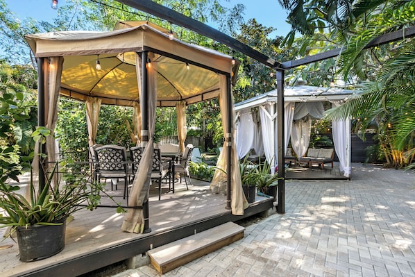 tropical oasis that has a BBQ area, hot tub, lounge seating, dining. and firepit
