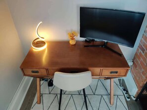Cozy workspace with a desk and chair, equipped with a lamp and a monitor for productivity and relaxation.
