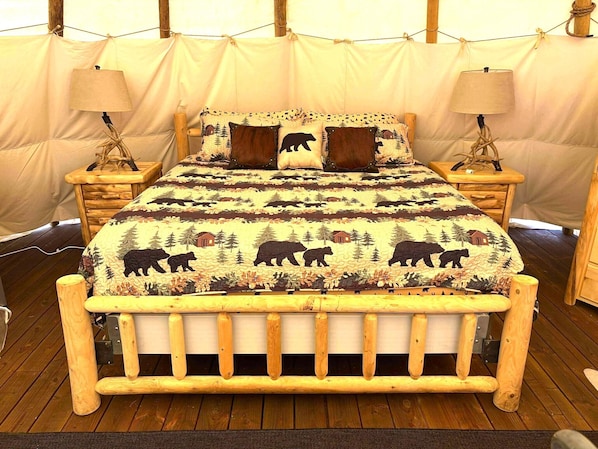 Center stage sits a deluxe king bed layered in crisp hotel linens, a lush comforter, and a mountain of plush pillows.
