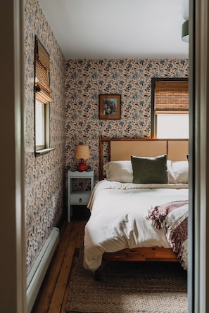 The master bedroom features a king bed, soft floral wallpaper, and warm tones that create a cozy, restful space for a peaceful night’s sleep.