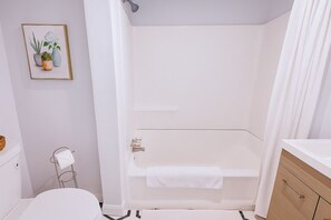 Clean shower-tub combo with fresh towels and a bright, modern design