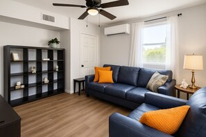 Bright living room with A/C, ceiling fan, cozy seating, and bookshelf