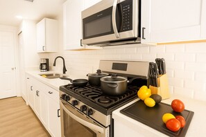 Fully stocked kitchen with gas stove, cookware, coffee maker, and microwave