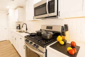 Fully stocked kitchen with gas stove, cookware, coffee maker, and microwave