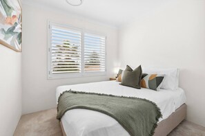 Drift off to sleep in the first bedroom with a queen bed, with plantation shutters that welcome in the breeze and morning light.
