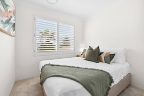 Drift off to sleep in the first bedroom with a queen bed, with plantation shutters that welcome in the breeze and morning light.