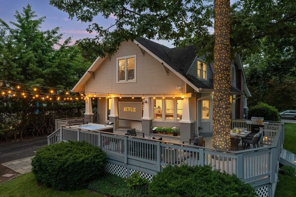Outdoor Entertainment Oasis: Enjoy movie nights under the string lights and stars on the expansive outdoor deck, featuring a 100" projector screen, 7-person luxury hot tub, fire-pit, and plenty of outdoor seating for the whole group.