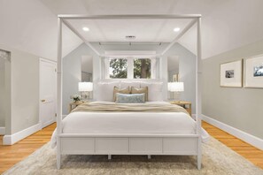Primary King Suite Retreat: An Elegant four-poster bed, premium memory foam mattress, Smart TV, and natural light make this king suite a tranquil escape.