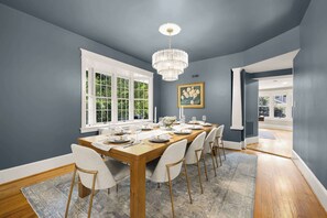 Stylish Dining Space: Host memorable meals in our elegant dining room, featuring comfortable seating for ten, stylish modern chairs, a statement chandelier, and natural light from large windows.