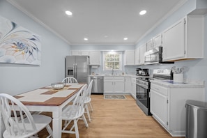 Modern kitchen with stainless steel appliances, coffee makers & utensils.