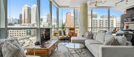 Living room with a 55" Smart TV, PS4, a record player and floor-to-ceiling, NW-facing windows with views of the Calgary tower & city skyline.