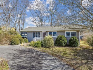 A picturesque angle highlights the house's inviting exterior with neatly manicured landscaping, framed by leafless trees that enhance the peaceful ambiance.