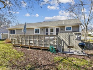 The expansive deck at the rear of the house is perfect for outdoor gatherings, showcasing a built-in BBQ area and shaded seating beneath a stylish umbrella.