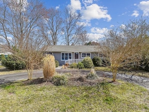 From this perspective, the property presents a serene setting, with well-kept shrubs and grasses complementing the attractive siding, all bathed in natural light.