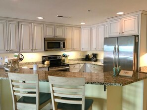 Step into this gorgeous beach-area condo's kitchen, featuring modern appliances, elegant cabinetry, and a spacious layout perfect for family meals.
