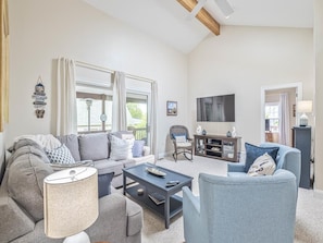 Cozy living room with vaulted ceilings, comfy seating, and abundant natural light—great for movie nights or relaxing.