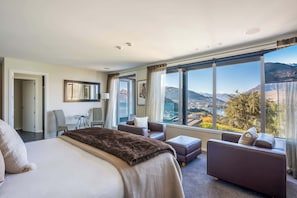 The spacious master bedroom features a luxurious king-size bed and large windows showcasing stunning lake and mountain views. Enjoy the privacy and convenience of your own modern ensuite bathroom.