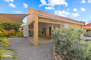 Villa Awa with folding shutter doors, open-plan kitchen, and spacious terrace with sunshade. Indoor and outdoor living blend seamlessly — perfect for relaxed outdoor living