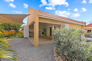 Villa Awa with folding shutter doors, open-plan kitchen, and spacious terrace with sunshade. Indoor and outdoor living blend seamlessly — perfect for relaxed outdoor living