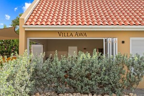 Villa Awa with open shutter doors to the terrace and lush tropical garden. Bright and airy, featuring high ceilings, a modern kitchen, and a comfortable lounge and dining area — ideal for relaxed island living
