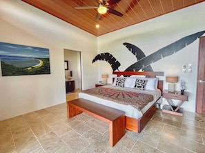 Suite #1 with king-size bed, ocean views, patio access, A/C, ceiling fan and en-suite bathroom.