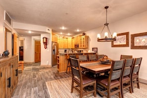 TPC-102C Rustic dining area with chandelier, wooden table, and cozy kitchen.