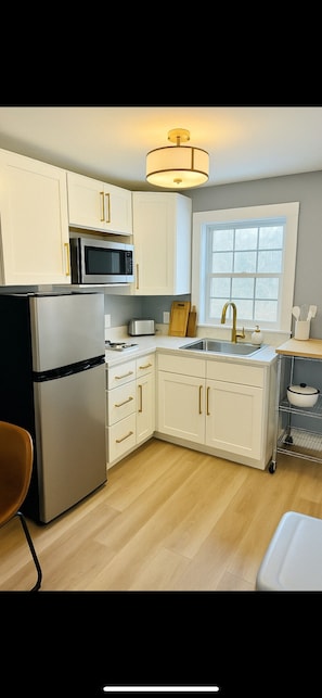 Enjoy the convenience of a fully updated kitchen featuring modern countertops, sleek cabinetry, a stainless steel sink, stovetop, microwave air fryer combo, and a refrigerator. Perfect for preparing meals for your day at the beach and park!