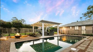 Sparkling pool, cozy firepit, and a beautifully lit outdoor lounge