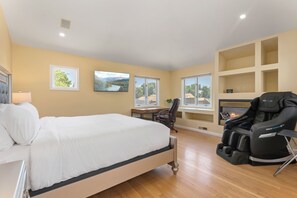 Bright, charming bedroom with plush king bed, workspace and massage chair for convenience.