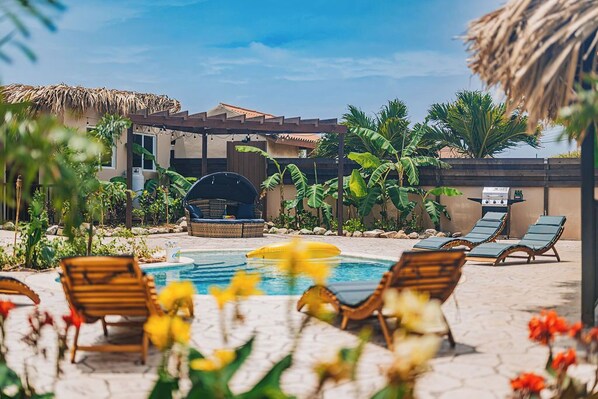 Vibrant pool area framed by tropical landscaping and wooden loungers – perfect for peaceful outdoor moments.

